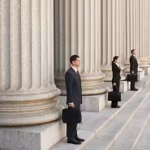 People in suits with briefcases standing in front of columns