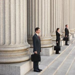 People in suits with briefcases standing in front of columns