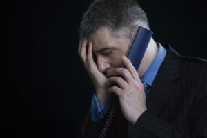 upset man on phone with debt collector