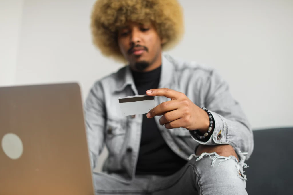 A person holding a credit card and looking at a laptop